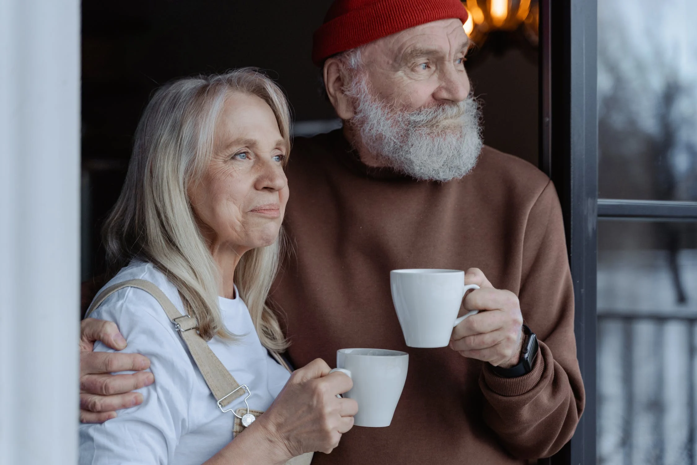 Older man and woman looking into the distance and drinking coffee