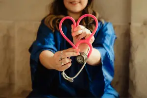 woman holding a stethoscope in the shape of a heart